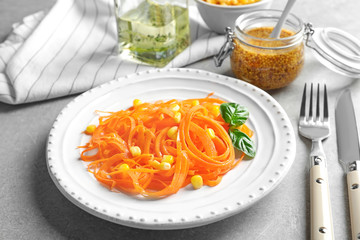 Plate with raw carrot spaghetti on table