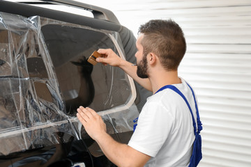 Worker tinting car window in shop