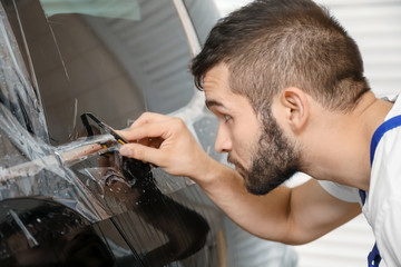 Obraz premium Worker tinting car window in shop