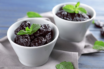 Bowls with tasty dried plums on table