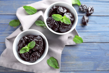 Bowls with tasty dried plums on table