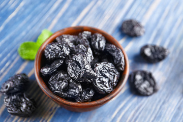 Bowl with tasty dried plums on table