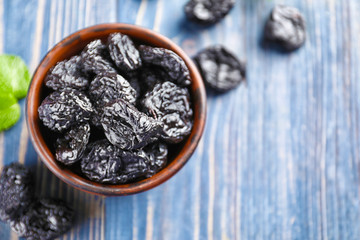 Bowl with tasty dried plums on table