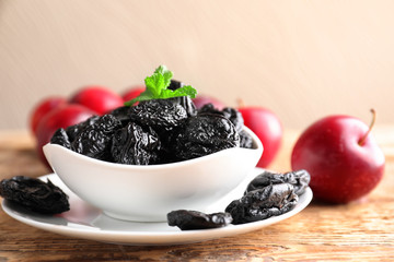 Bowl with tasty dried plums on table