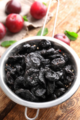 Collander with tasty dried plums on table