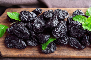 Board with tasty dried plums on table