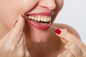 Fototapeta premium Smiling middle aged woman with ideal strong white teeth, teethcare. Selective focus. Healthcare, stomatological concept for dentists. Cleaning teeth with tooth thread.