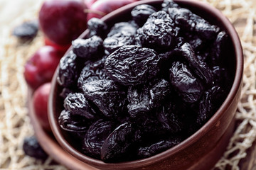 Bowl with tasty dried plums on table