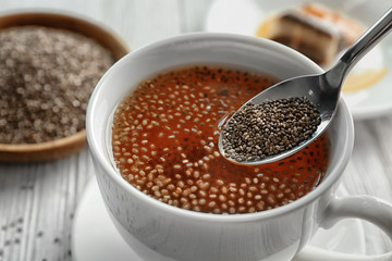 Adding chia seeds to tea in cup, closeup