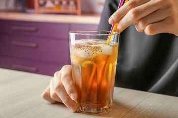 Woman holding glass of tea with chia seeds on table