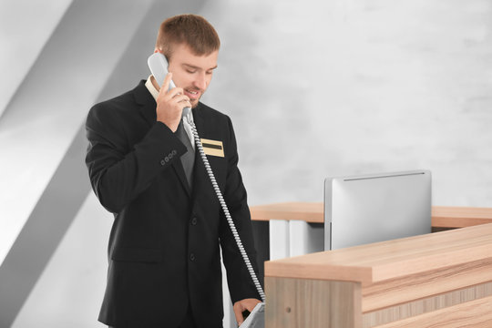 Male receptionist talking on phone in hotel