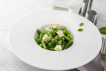 Plate with delicious green beans salad on wooden table