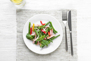 Plate with delicious green beans salad on wooden table