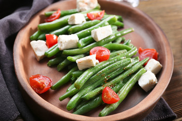 Plate with delicious green beans salad on wooden table, closeup