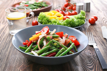 Bowl with delicious green beans salad on wooden table