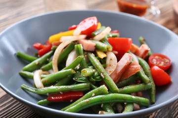 Bowl with delicious green beans salad on wooden table, closeup