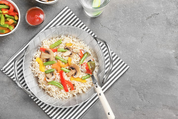 Composition with pan of brown rice and vegetables on table