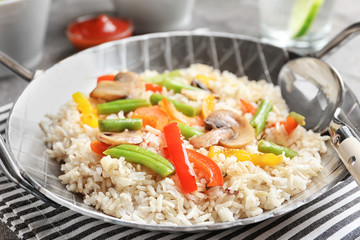 Brown rice with vegetables and mushrooms in frying pan