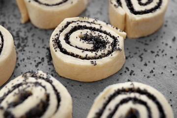 Raw rolls with poppy seeds on table, close up