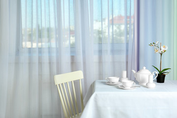 Serving table near window with modern curtains in room