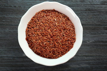 Bowl with raw rice on wooden table
