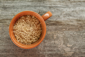 Cup with raw rice on wooden table