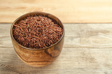 Bowl with raw rice on wooden table