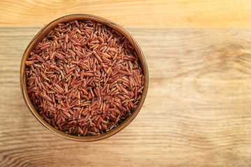 Fototapeta na wymiar Bowl with raw rice on wooden table