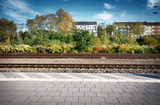 Bahnhof Bahnsteig gepflastert horizontal mit Markierungen und H&auml;usern
