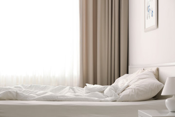 Fototapeta na wymiar Cozy bed near window with beautiful curtains in room
