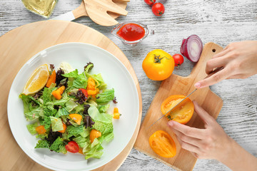 Woman cutting tomatoes for kale salad on table