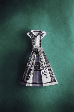 An origami dress made from hundred US dollar bill on green background