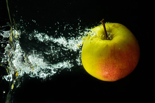A red-green apple in a stream of water