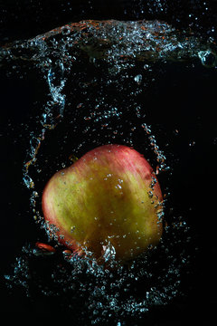 A red-green apple in a stream of water