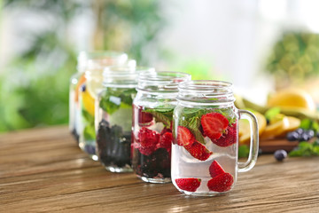Fototapeta na wymiar Mason jars of infused water with fruits and berries on wooden table