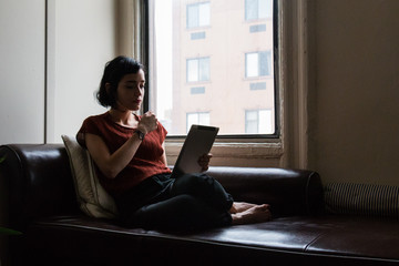 Brunette on the sofa reading a digital tablet