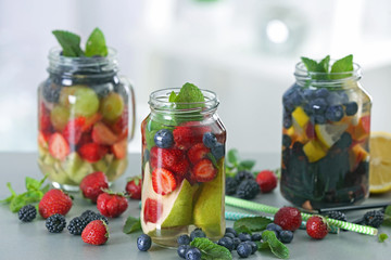 Fototapeta na wymiar Mason jars of infused water with fruits and berries on table