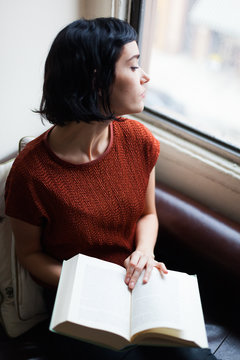 Brunette reading a book on the sofa