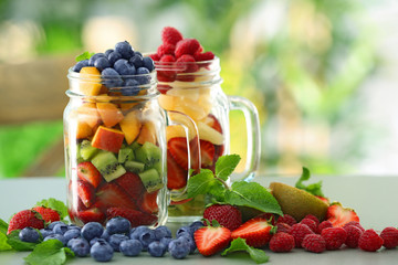 Mason jars with fruits and berries on table