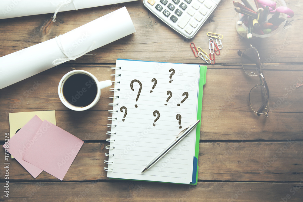 Poster questions text on notepad and office tools on wooden table