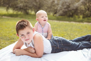 Two siblings laying on a blanket on a sunny summer day. Backlight, shallow depth of field.