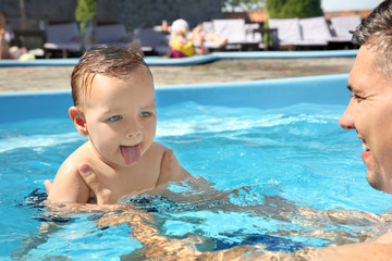Fototapeta na wymiar Child swimming lesson. Cute little boy learning to swim with father in pool