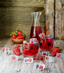 Summer berry lemonade with frozen berries on a wooden rustic table, selective focus