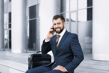 Handsome successful businessman talking on mobile phone outdoors