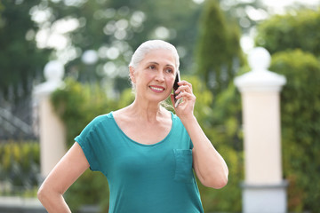 Fototapeta premium Beautiful senior woman talking on mobile phone outdoors
