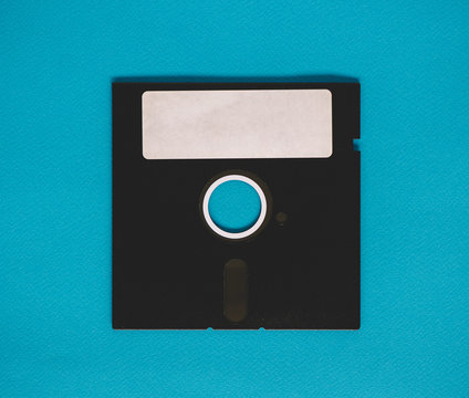 Old floppy disk sitting on a blue background.