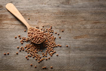 Spoon with brown lentils on wooden table