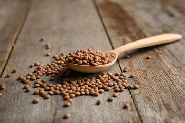 Spoon with brown lentils on wooden table