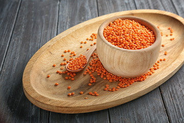 Bowl and spoon with red lentils on wooden tray