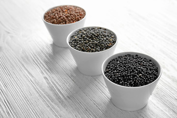 Bowls with different lentils on wooden table